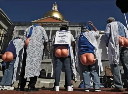  ?? NANcy LANE / HERALD STAFF ?? NO IFS, AND, OR BUTTS: Members of the Senior Action Council, wearing hospital gowns and plastic bottoms, hold a rally outside the State House on Monday, calling for lawmakers to use American Rescue Plan money to help seniors near the poverty line save money on monthly health care costs.