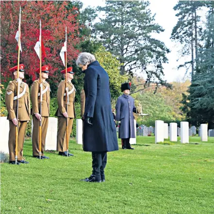  ??  ?? Left: Theresa May takes a silent moment at St Symphorien Military Cemetery in Mons, Belgium, at the grave of George Ellison, the last British soldier to die on Armistice Day, November 11, 1918. Far left, the Prime Minister lays a wreath at the grave of John Parr, the first British soldier to be killed in 1914