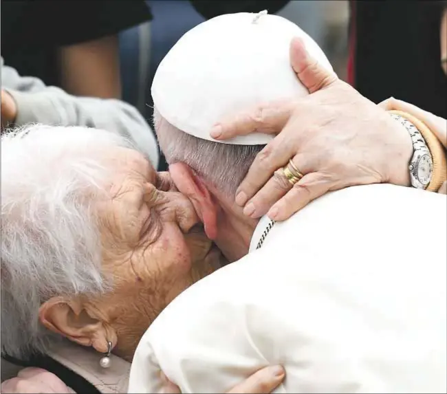  ?? AFP Photo/ Vincenzo Pinto ?? Una anciana besa al Papa Francisco durante su visita a la parroquia San Pablo de la Cruz, en el barrio romano de Corviale, en abril de 2018