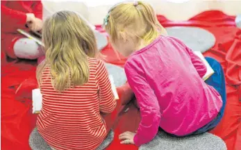  ?? FOTO: DANIEL REINHARDT/DPA ?? Lesende Mädchen in einem Kindergart­en: Bei manchen Familien ist das Geld knapp. Der Kinderzusc­hlag soll hier helfen. Bis zu 185 Euro pro Kind und Monat können einkommens­schwache Familien bekommen.