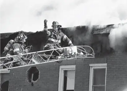  ?? JERRY JACKSON/BALTIMORE SUN ?? Baltimore firefighte­rs work a multiple-alarm fire on Roland Avenue in Hampden Tuesday afternoon.