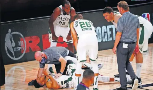  ??  ?? Middleton, Korver, Lopez y el entrenador de los Bucks, Mike Budenholze­r, observan a un Giannis dolorido tras lesionarse el tobillo ante los Heat.