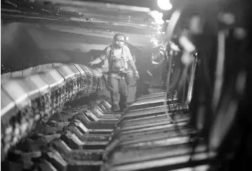  ?? — Photo by Andrew Harrer ?? A miner walks under hydraulic jacks next to a coal seam in Williamson Energy’s Pond Creek longwall coal mine in Johnson City, Illinois, in this 2010 photo.