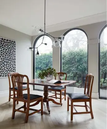  ??  ?? DINING ROOM A dramatic monochrome painting – ‘Watiya Yuninya (Tree And Seeds)’ by the acclaimed indigenous artist Mitjili Napurrula – is the star of the dining room (above left), where a ‘Y Chandelier’ pendant by Douglas And Bec is suspended above the handsome antique dining setting. “The table is made from one piece of mahogany and is what was called a ‘breakfast table’,” explains Annette. “Ian loves antiques and he found it, along with the Georgian chairs, about 30 years ago in an antique shop.”