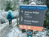  ?? HAVEN DALEY/AP ?? A hiker walks along a snow-covered trail Friday at Mount Tamalpais State Park in Mill Valley, Calif.