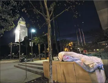  ?? Francine Orr Los Angeles Times ?? A PERSON SLEEPS downtown near City Hall. The county homeless population is nearly 60,000, and as one government worker says: “Despite the huge investment we’ve made, the endgame is not clear.”