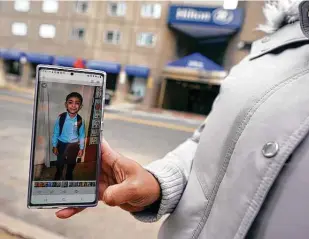  ?? Charles Krupa / Associated Press ?? Hotel housekeepe­r Esther Montanez holds up a photo of her 5-year-old son, Richard, outside the Hilton Back Bay hotel in Boston. Montanez refuses to give up hope of returning to her cleaning job at the hotel, which she held for six years until being furloughed in March 2020.