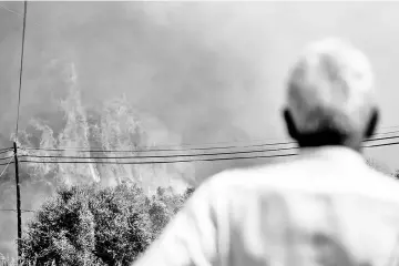  ??  ?? A man watches the progressio­n of a wildfire close to Monchique, in Algarve, Portugal.