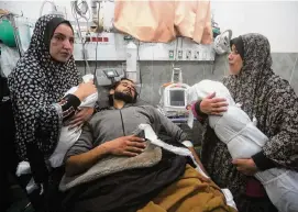  ?? Hatem Ali/Associated Press ?? Palestinia­n women show the bodies of two young children to their wounded father Tuesday in Rafah. They died in a pre-dawn strike on their home.