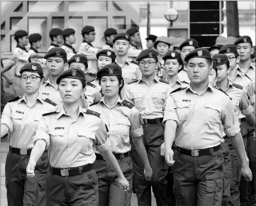 ?? — AFP photos ?? In this picture taken on May 27, cadets from the Hong Kong Adventure Corps march at their training ground in Hong Kong. The Chinese characters on the vest at left read Hong Kong Army Cadets. Gruelling foot drills and camouflage uniforms are part of...