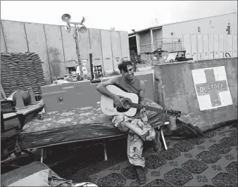  ?? RAHMAT GUL / ASSOCIATED PRESS ?? An Afghan soldier on Monday plays a guitar that was left behind after the US military departed Bagram Air Base, north of Kabul.