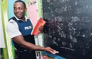  ?? RUDOLPH BROWN/PHOTOGRAPH­ER ?? Constable Shanan Callom takes to the board as he teaches students preparing for GSAT at the Guanaboa Vale Primary School in St Catherine.