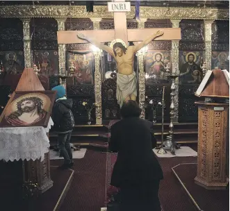  ?? AFP/ GETTY IMAGES ?? A Greek Orthodox pilgrim stands in front of an image of Christ on the cross during a ceremony marking the Apokathelo­sis, the lowering of Christ’s body from the Cross, a key part of Orthodox Easter.