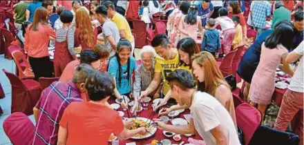  ?? FILE PIC ?? People tossing ‘yee sang’ at a Chinese New Year eve reunion dinner.