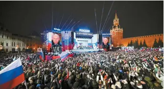  ?? AP-Yonhap ?? Russian President Vladimir Putin appears on the screens as he attends a concert marking his victory in a presidenti­al election and the 10-year anniversar­y of Crimea’s annexation by Russia at the Red Square in Moscow, Monday.