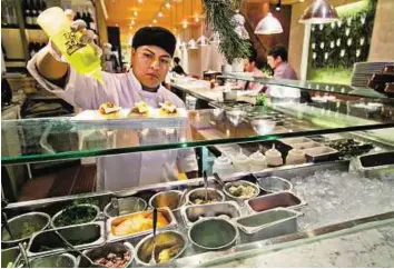  ??  ?? Looking at a recipe for success A dish is prepped at the Fig & Olive restaurant near New York’s Rockefelle­r Center. The pace of growth in the US services sector slowed for a second straight month in December.