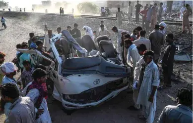  ??  ?? Residents gather around the wreckage of the van alongside the railway track in Farooqabad area of Punjab’s Sheikhupur­a district.