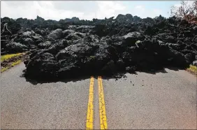  ?? JAE C. HONG/AP PHOTO ?? Center lane lines are partially visible along the lava-covered road in the Leilani Estates subdivisio­n near Pahoa, Hawaii, Friday. Kilauea has destroyed more than 35 structures since it began releasing lava from vents about 25 miles east of the summit...