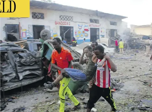  ?? FARAH ABDI WARSAMEH / THE ASSOCIATED PRESS ?? Somalis carry away a man injured by a car bomb at a hotel in Mogadishu, Somalia on Saturday. The attack, which killed 23, as well as one two weeks ago that killed 350 on a city street, has shaken public confidence in the military.