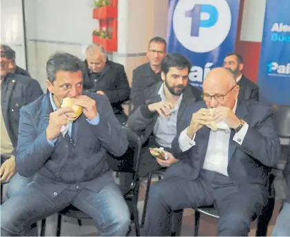  ??  ?? Conurbano. Massa y el ex alcalde Giuliani se comen un choripán en la recorrida por Villa Madero.