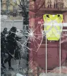  ??  ?? A smashed window displaying a yellow vest, showing support for protesters and for protesters not to attack the building, in Paris.
