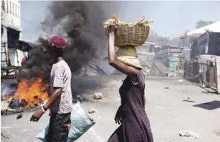  ?? AP ?? Desórden. Una pareja avanza frente a una goma que arde, durante los disturbios del lunes pasado.