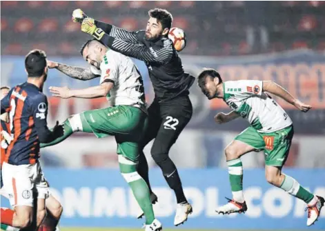  ??  ?? ► El delantero Matías Donoso salta por el balón junto con el arquero de San Lorenzo, Nicolás Navarro.