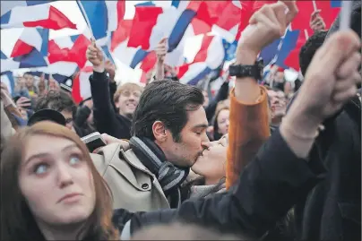  ?? AP PHOTO ?? Supporters of French independen­t centrist presidenti­al candidate, Emmanuel Macron kiss as they celebrate outside the Louvre museum in Paris, Sunday. Centrist Emmanuel Macron is France’s next president, putting a 39-year-old political novice at the helm...