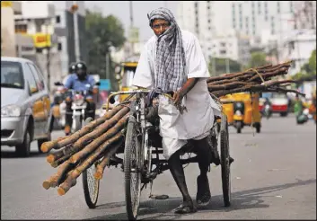  ?? MAHESH KUMAR A./THE ASSOCIATED PRESS ?? A laborer covers himself with a cloth to protect from the sun as he pulls a rickshaw carrying wooden logs on a hot summer afternoon Friday in Hyderabad, India.