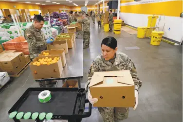  ?? Photos by Jim Gensheimer / Special to The Chronicle ?? Gabriella Flores of Sacramento carries a box to stack on a pallet at Second Harvest of Silicon Valley.