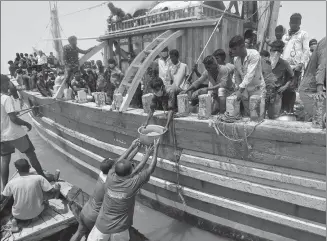  ?? PRASHANT WAYDANDE / REUTERS ?? Local fishers offer a container with food to other fishers, who said they were refused entry at two ports after traveling in the Arabian Sea to reach their home in Dahanu, India, on Friday. A nationwide lockdown to fight COVID-19 continues in the country.