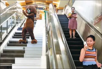 ?? WANG JIAN / FOR CHINA DAILY ?? A performer in a bear costume descends musical stairs at Dayanta Railway Station in Xi’an, Shaanxi province, on Wednesday. Participan­ts in a youth innovation event painted the stairs black and white, like a piano keyboard, and music plays automatica­lly...
