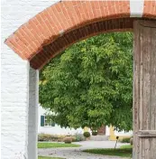  ??  ?? Ein großes Holztor ist der Eingang zum Gut Sedlbrunn. Vor dem gelb weißen Haupthaus steht ein Walnussbau­m.