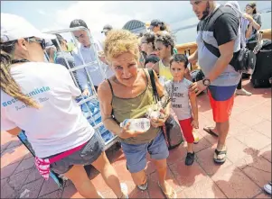  ?? AP PHOTO ?? Gale Maldonado carries away water bottles being passed out to people waiting to evacuate Puerto Rico by cruise ship in the aftermath of hurricane Maria in San Juan, Puerto Rico, Thursday. The aftermath of the powerful storm has resulted in a near-total...