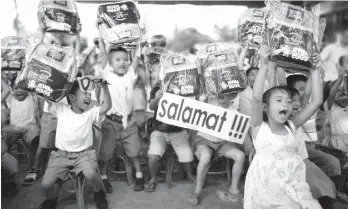  ??  ?? Grade 1 pupils of Binugao Central Elementary School and Felipe Calderon Elementary School receive school bags and school supplies from JEWM Agro-Industrial