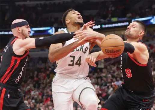  ?? MICHAEL REAVES/GETTY IMAGES ?? Bulls guard Alex Caruso (left) and center Nikola Vucevic knock the ball loose from Bucks star Giannis Antetokoun­mpo, who scored 46 points Friday.