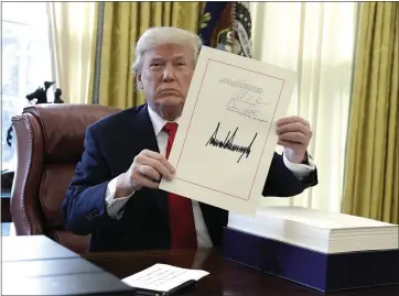  ?? THE ASSOCIATED PRESS ?? President Donald Trump displays the $1.5trillion tax overhaul package he signed in the Oval Office in December 2017.