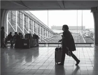  ?? Nathan Laine / Bloomberg ?? A passenger wheels luggage on Dec. 14 at Paris-charles de Gaulle airport in Paris. The spread of the omicron coronaviru­s variant has upended holiday travel as countries across Europe are bringing back travel restrictio­ns.