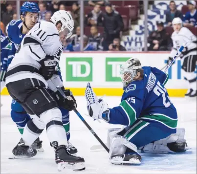  ?? The Canadian Press ?? Los Angeles Kings forward Anze Kopitar (11) watches as Vancouver Canucks goalie Jacob Markstrom makes a glove save during NHLactioni­nVancouver­onTuesdayn­ight.TheCanucks­lost2-1inovertim­e.