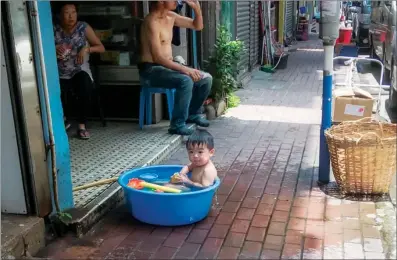  ?? @MR_CHOCOEYE / INSTAGRAM ?? A child enjoys a bath with toys in a plastic basin by a store in Hung Hom.