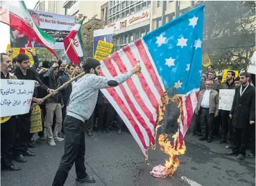  ?? /Bloomberg ?? Fierce opposition: A protester sets fire to the US flag on the anniversar­y of the US embassy seizure, in Tehran, Iran, on November 4. Iran’s Supreme Leader Ayatollah Khamenei said Trump’s policies are opposed by most government­s..