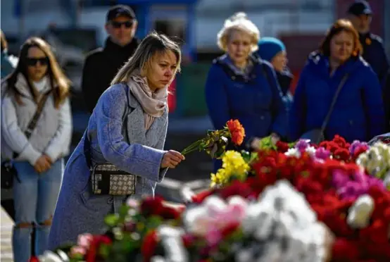  ?? ALEXANDER ZEMLIANICH­ENKO/ASSOCIATED PRESS ?? A woman placed flowers at a makeshift memorial in front of the Moscow concert hall where at least 143 people were killed.