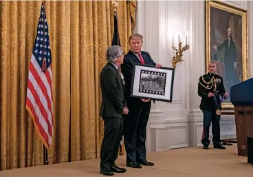  ??  ?? HONOR BOUND Ut, with Donald Trump at the White House medal ceremony, where the president showed off his signed copy of the photograph­er’s iconic “Napalm Girl” picture.