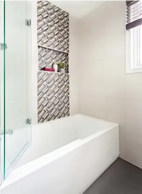  ??  ?? La céramique à motifs ponctue avec originalit­é le coin bain-douche équipé d'une porte vitrée amovible. Cette insertion ajoute de la classe au revêtement en carreaux blancs sur lequel se réfléchit la lumière entrant par la fenêtre.