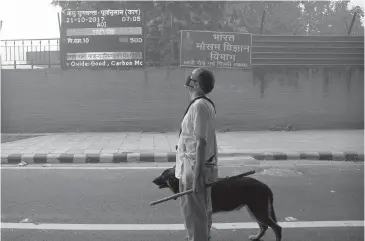  ?? MANISH SWARUP, THE ASSOCIATED PRESS ?? An Indian man looks at the air-quality board outside the India Meteorolog­ical Department in New Delhi. A report from the Lancet medical journal says environmen­tal pollution — from filthy air to contaminat­ed water — is killing more people every year...