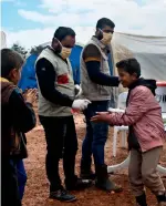  ?? AP ?? Aid workers disinfect the hands of Syrian children, living at a camp for internally displaced persons in northern Syria.—