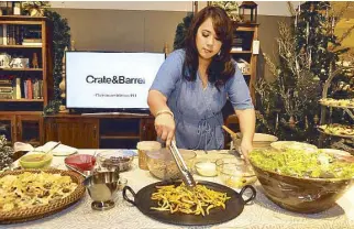  ??  ?? Sabrina Go of Mothers Who Brunch spreads holiday cheer by making holiday poutine for everyone during the launch of #Christmasw­ithCratePH.