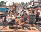  ?? AP ?? A group of people helps clear debris and salvage items from Pawn Depot after a tornado touched down Saturday in Jonesboro, Ark.