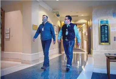  ?? EDDIE MOORE/JOURNAL ?? Gilbert C’ de Baca, left, and Gregory Segura, both staffers with the Senate sergeant-at-arms office, patrol the halls of the Roundhouse on Friday to check on mask-wearing compliance. COVID-19 testing at the Capitol has revealed five positive cases over the last two weeks.