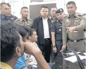  ?? SITTHIPONG CHAROENJAI ?? Deputy Tourist Police Bureau chief Surachate Hakparn talks to two Thais and a Chinese national arrested on suspicion of serving as nominees for a Chinese-owned tour firm accused of cheating businesses on Koh Samui.